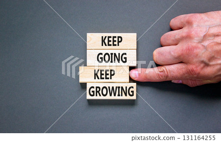 Keep going and growing symbol. Concept words phrase Keep going keep growing on beautiful wooden blocks. Beautiful grey background. Businessman's hand. Business Keep going growing concept. Copy space. Keep going and growing symbol. Concept words phrase Keep going keep growing on beautiful wooden blocks. Beautiful grey background. Businessman's hand. Business Keep going growing concept. Copy space. 131164255