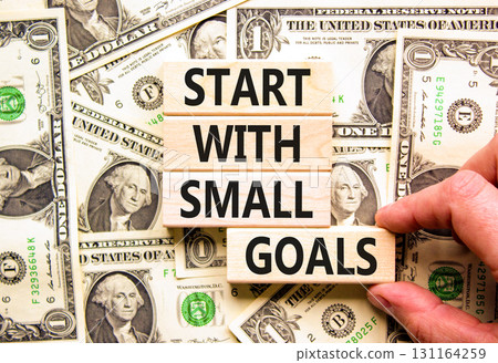 Start with small goals symbol. Concept words phrase Start with small goals on beautiful blocks. Dollar bills. Beautiful dollar bills background. Business Start with small goals concept. Copy space 131164259
