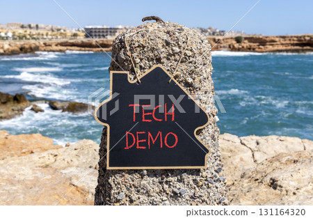 Tech demo symbol. Concept word Tech demo on beautiful black blackboard. Beautiful stone and blue sea sky background. Black blackboard. Business tech demo concept. Copy space. 131164320