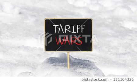 Trade tariff wars symbol. Concept word Tariff wars on beautiful black blackboard. Beautiful white snow background. White snow. Black blackboard. Business trade tariff wars concept. Copy space. Trade tariff wars symbol. Concept word Tariff wars on beautiful black blackboard. Beautiful white snow background. White snow. Black blackboard. Business trade tariff wars concept. Copy space. 131164326
