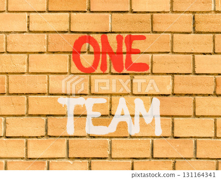 One team symbol. Concept word One team on beautiful brown brick wall. Beautiful brown brick wall background. Brick wall. Business one team concept. Copy space. One team symbol. Concept word One team on beautiful brown brick wall. Beautiful brown brick wall background. Brick wall. Business one team concept. Copy space. 131164341