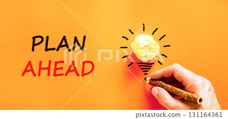 Plan ahead symbol. Concept word Plan ahead on beautiful orange paper. Businessman's hand. Light bulb icon. Beautiful orange paper background. Business plan ahead concept. Copy space. Plan ahead symbol. Concept word Plan ahead on beautiful orange paper. Businessman's hand. Light bulb icon. Beautiful orange paper background. Business plan ahead concept. Copy space. 131164361