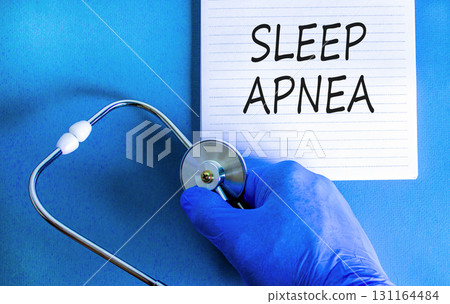 Sleep apnea symbol. Concept words Sleep apnea on beautiful white note. Doctor's hand in blue medical glove. Stethoscope. Beautiful blue background. Medical healthy lifestyle sleep apnea concept. 131164484