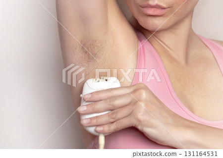 Woman epilates her armpit with an electric epilator device photo Woman epilates her armpit with an electric epilator device photo 131164531