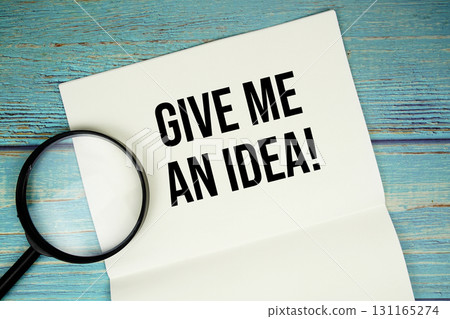 Give Me An Idea! text written on notepad with magnifying glass flat lay on wooden background Give Me An Idea! text written on notepad with magnifying glass flat lay on wooden background 131165274