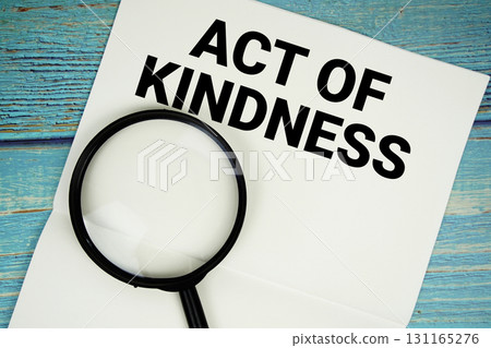 Act Of Kindness text written on notepad with magnifying glass flat lay on wooden background 131165276