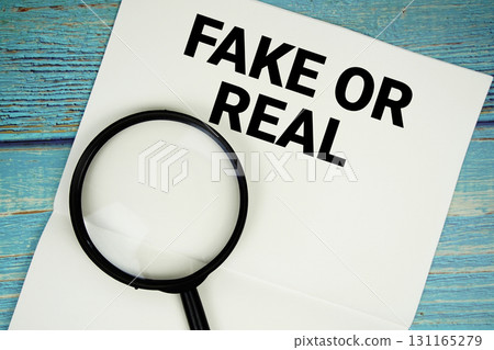 Fake Or Real text written on notepad with magnifying glass flat lay on wooden background Fake Or Real text written on notepad with magnifying glass flat lay on wooden background 131165279