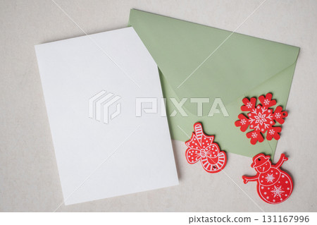 Christmas background. Empty white blank greeting or invitation card with envelope and Christmas decoration on concrete texture background. 131167996