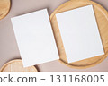Empty white blank greeting or invitation card, wooden plate on beige background. 131168005