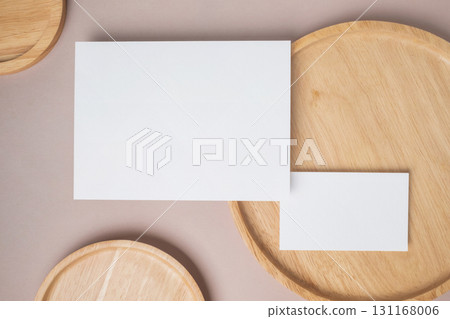 Empty white blank greeting or invitation card, name card, wooden plate on beige background. Mock up presentation. 131168006