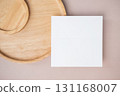 Empty white blank greeting or invitation card, wooden plate on beige background. 131168007