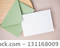 Empty white blank greeting or invitation card, envelope, wooden plate on beige background. 131168009