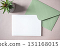 Empty white blank greeting or invitation card, green envelope, cactus on beige background. 131168015