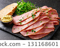 Thin slices of ham arranged on stone board with mustard dip bread and fresh greens; ham presentation looks appetizing as ham setup suggests rustic meal and festive table 131168601