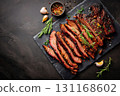 Sliced brisket on slate board; juicy brisket with pepper crust and coarse spices, garnished with rosemary, garlic; tender brisket ideal for bbq menu, rustic serving for cookout, cozy grill theme 131168602