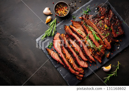 Sliced brisket on slate board; juicy brisket with pepper crust and coarse spices, garnished with rosemary, garlic; tender brisket ideal for bbq menu, rustic serving for cookout, cozy grill theme Sliced brisket on slate board; juicy brisket with pepper crust and coarse spices, garnished with rosemary, garlic; tender brisket ideal for bbq menu, rustic serving for cookout, cozy grill theme 131168602
