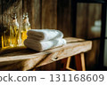 Sunlit towels on rustic bench, towels folded crisp with soft edges, window shadow draws patterns across wood grain, bottles with aroma oil blur behind, towels promise clean comfort and cozy spa mood 131168609