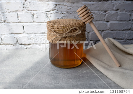 Honey jar with honeycomb and wood spoon stay on the stone table with napkin. Honey jar with honeycomb and wood spoon stay on the stone table with napkin. 131168764