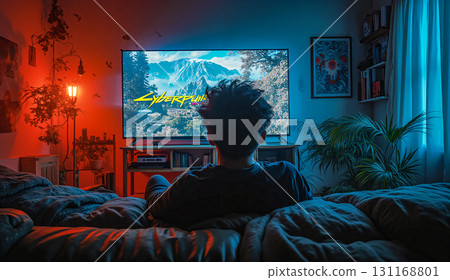 Cyberpunk gamer immersed in a neon-lit gaming session. Young man sitting on a bed immersed in gaming on a large television screen displaying "Cyberpunk" with a mountain landscape. 131168801