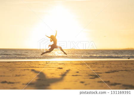 Ballerina is jumping on the beach at sunset, showing freedom and happiness 131169391