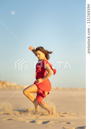 Dancer performing on sandy beach at sunset with moon in sky 131169394