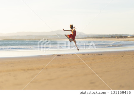 Ballerina performing a jump on the beach at sunset 131169456