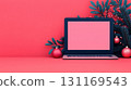 modern laptop on vibrant pink background, surrounded by festive decorations like ornaments and greenery, creating cheerful workspace atmosphere 131169543