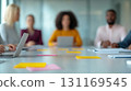 Diverse group of business leaders collaborating in modern office setting. atmosphere is focused and productive, with laptops and colorful sticky notes on table 131169545