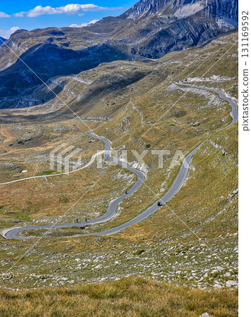 Scenic view of a winding serpentine road in Sedlo, Durmitor National Park, Montenegro, with mountains and hills in the distance, perfect for travel, adventure, and nature content 131169592