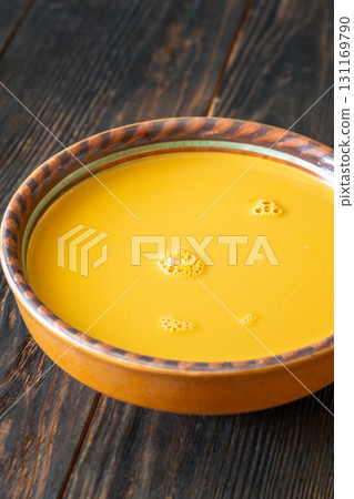 Creamy bisque served in clay bowl placed on rustic wooden table 131169790