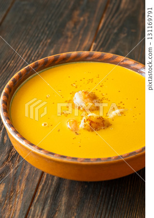 Clay bowl of creamy shrimp bisque served warmly on rustic wooden table 131169791