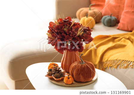 Thanksgiving living room decor with a coffee table, pumpkins and a floral arrangement. Thanksgiving living room decor with a coffee table, pumpkins and a floral arrangement. 131169901