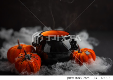 Halloween Candle in Cauldron with Pumpkins and Fog Halloween Candle in Cauldron with Pumpkins and Fog 131169908