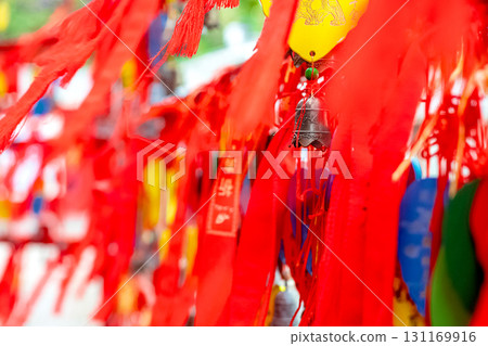 Carved bronze bells and red ribbons with Chinese characters at a temple. 131169916