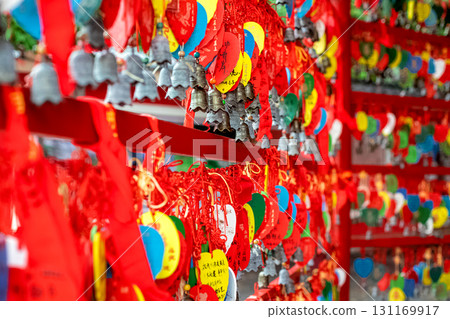 Carved bronze bells and red ribbons with Chinese characters at a temple. 131169917