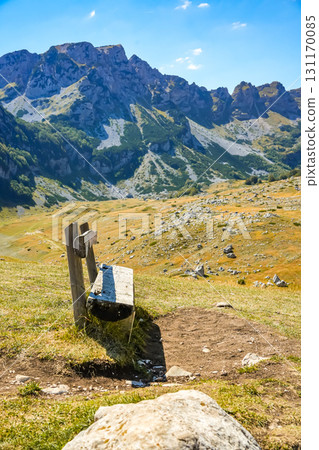 Wooden bench on hillside with panoramic view of Sedlo hills and Durmitor mountains in Montenegro. Peaceful autumn travel and nature background. 131170085