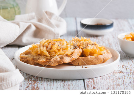 Appetizing croutons with stewed apple strips on a plate on the table 131170195