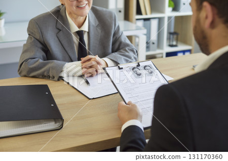 HR interview, holding resume with photos presenting information during formal interaction HR interview, holding resume with photos presenting information during formal interaction 131170360
