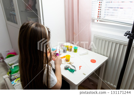 Little girl with long brown hair playing with plasticine Little girl with long brown hair playing with plasticine 131171244