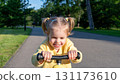 Toddler on scooter. Yellow scooter ride girl. Child park activity summer. 131173610