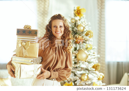 Woman with Gold Gifts by Snowy Christmas Tree Woman with Gold Gifts by Snowy Christmas Tree 131173624