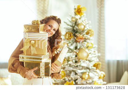 Elegant Woman with Gold Presents by Flocked Tree Elegant Woman with Gold Presents by Flocked Tree 131173628