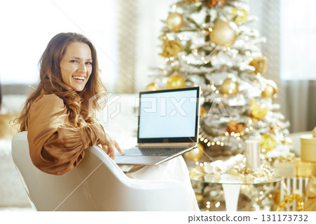 Smiling Woman with Laptop by Festive Christmas Tree Smiling Woman with Laptop by Festive Christmas Tree 131173732