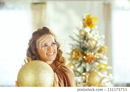 Woman Looks Up Holding Gold Christmas Ornament Woman Looks Up Holding Gold Christmas Ornament 131173753