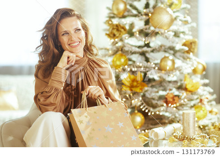 Elegant Woman Holding Shopping Bag by Christmas Tree 131173769