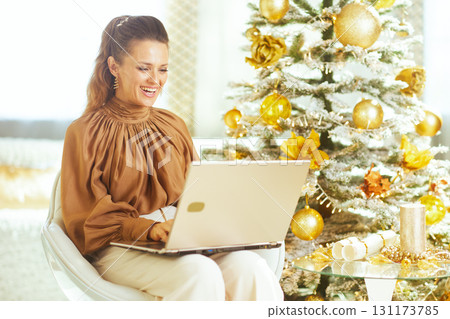 Woman Using Laptop by Christmas Tree at Home 131173785