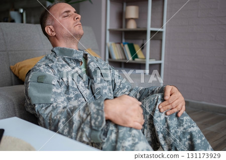 Soldier sitting on the floor suffering from post-traumatic stress disorder 131173929