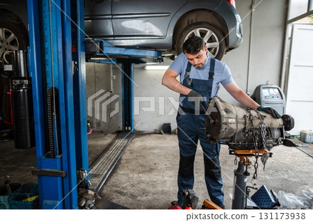 Mechanic repairing gearbox in car service 131173938