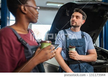 Mechanics taking a coffee break and discussing about car repair 131173944