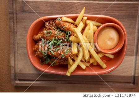 Crispy chicken wings served with golden fries and dipping sauce on wooden table Crispy chicken wings served with golden fries and dipping sauce on wooden table 131173974